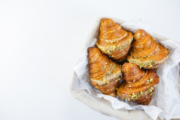 Croissants resting in a rustic wicker basket atop a clean white table