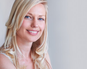 Natural beauty. A gorgeous blonde woman smiling while isolated on a grey background.