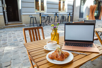 a freelancer's workplace in a cafe with a croissant and coffee