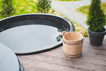 Wash basin wooden bucket for bath. Sauna equipment. Jacuzzi on the terrace, sunny patio.