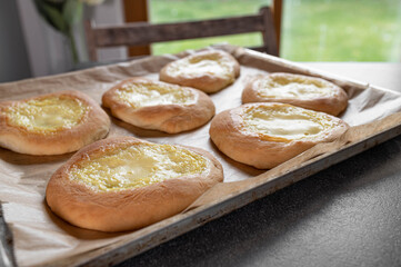 Naklejka na ściany i meble Fresh baked yeast pastries with sour cream, vanilla pudding filling on a baking sheet