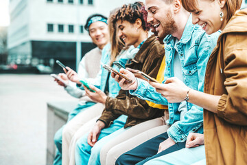 Happy group of multiracial teens using smart mobile phone outdoors - Diverse university students...
