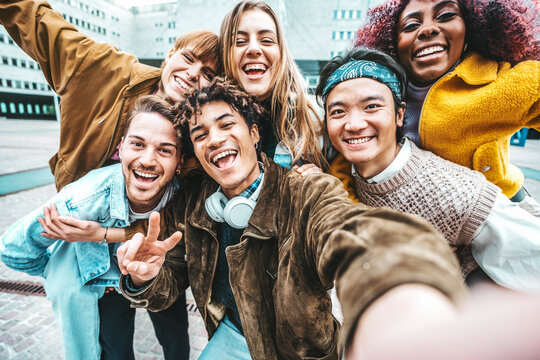 Multiracial friends taking selfie pic outdoors - Happy young people having fun walking on city street - Life style concept with guys and girls hanging outside - College students smiling at camera