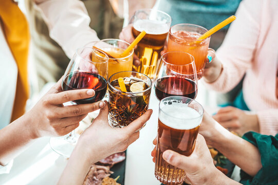 Close up image of hands holding cocktail glasses at bar restaurant - Young people having fun hanging out on weekend day - Food and beverage concept with guys and girls drinking alcohol together