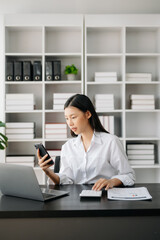 Asian businesswoman working in the modern office with working notepad, tablet and laptop documents