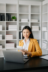 Young attractive Asian female office worker business suits smiling at camera in modern office .