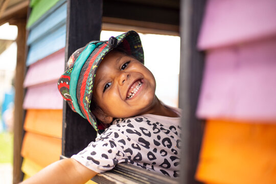 Young Aboriginal girl in a cubby house smiling out window
