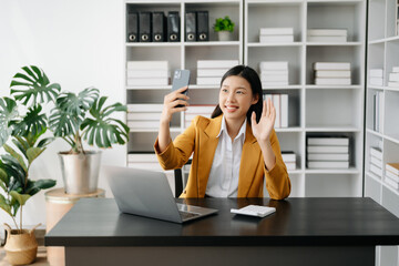  Working woman concept a female manager attending video conference and holding tablet, smatrphone in modern office