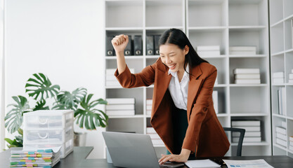 Asian business woman are delighted and happy with the work they do on their tablet, laptop and taking notes at the office.