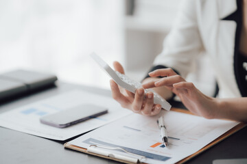 businessman or accountant hand working on calculator to calculate business data, accounting document and laptop computer at office, business concept