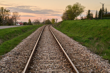 Fototapeta na wymiar A single railway line on the embankment along the road bending over the horizon