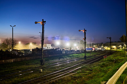 A gloomy, gray freight train station on the outskirts of the city at night