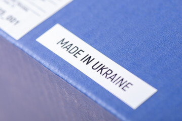 Obraz premium Made in Ukraine inscription on blue paper box of cosmetics, close up. Manufacturing perfumes, creams and other cosmetics in Ukraine