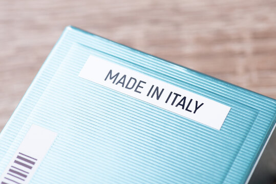 Blue paper box of perfume with inscription Made in Italy. Close up photo of the name of origin country, where the product was made