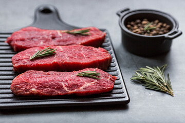 Fresh meat. Raw beef steaks with rosemary and spices on a stylish blackboard. Flat top view.