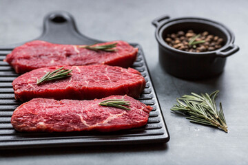Fresh meat. Raw beef steaks with rosemary and spices on a stylish blackboard. Flat top view.