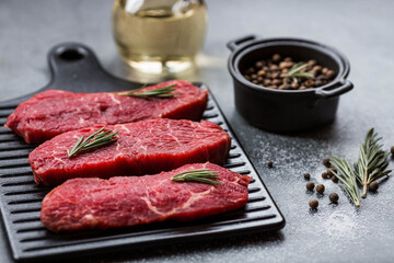 Fresh meat. Raw beef steaks with rosemary and spices on a stylish blackboard. Flat top view.