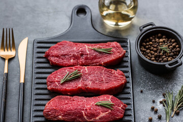 Fresh meat. Raw beef steaks with rosemary and spices on a stylish blackboard. Flat top view.
