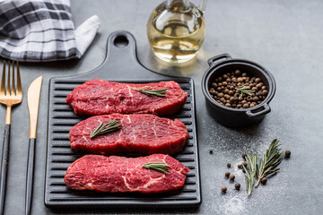 Fresh meat. Raw beef steaks with rosemary and spices on a stylish blackboard. Flat top view.