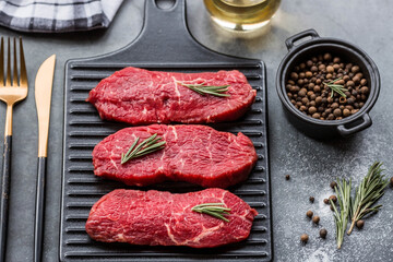 Fresh meat. Raw beef steaks with rosemary and spices on a stylish blackboard. Flat top view.