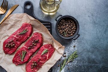 Fresh meat. Raw beef steaks with rosemary and spices on parchment paper on a stylish board. Flat top view.