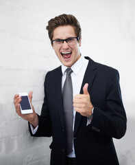 He found a great business application. A handsome young businessman holding a smartphone while giving you the thumbs up.