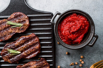 Fresh meat. Grilled beef steaks with rosemary, spices and tomato paste on a stylish board. Flat top view.
