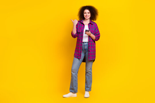 Full length photo of attractive lady wear checkered magenta jacket jeans direct finger mockup phone share video isolated on yellow color background