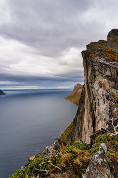 People looking over the Mefjorden fjord from a very high cliff leading up to mountain Hesten in Troms og Finnmark, Norway