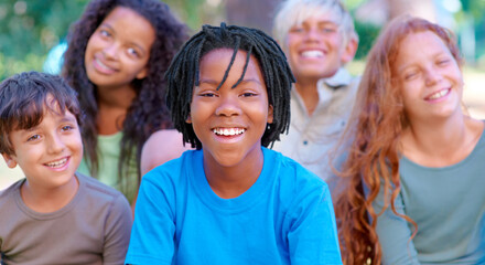 Summer camp fun. A group of happy kids smiling at the camera while sitting outside.