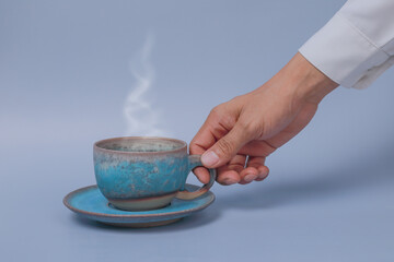 hand holding cup of tea on light blue background