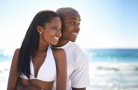 Looking forward to the future together. A young african-american couple looking away while enjoying a day at the beach.