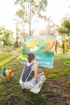 Young aussie person working on landscape painting in nature outdoors