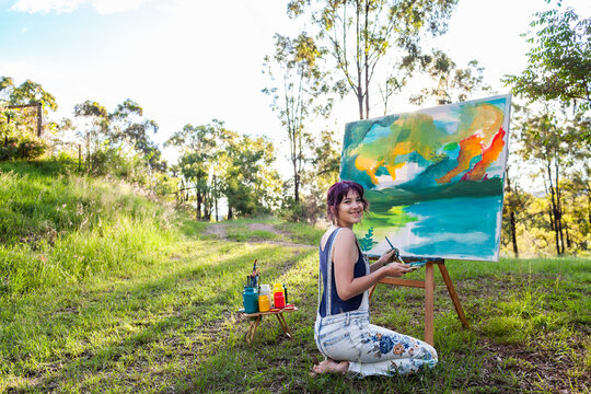 portrait of young australian artist beside painting outdoors