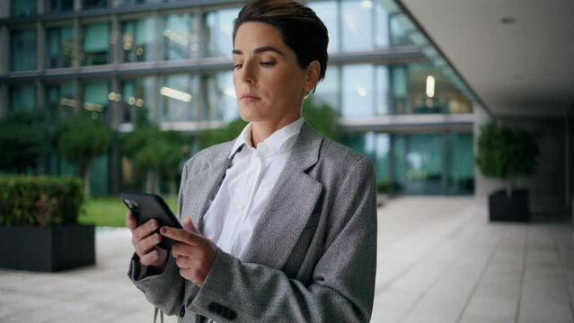 Annoyed businesswoman text phone at office center. Nervous executive send reply