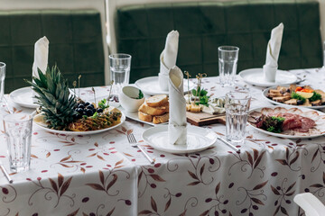 Served table food buffet in restaurant for wedding or birthday party dinner dishes. Assorted meats, chives, bacon, salami, hard cheese with mould, herbs, ananas, banana, grapes, fruits
