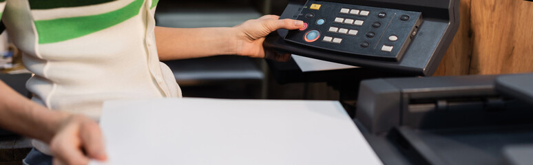 cropped view of publisher holding blank paper near printer in copy center, banner.