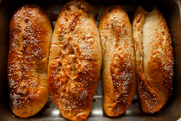 Close up shot homemade food baking concept. Fresh hot soft fluffy ginger golden brown sesame seeds buns pie bread dessert pastry in loaf pan. Bakery products, image with copy space.