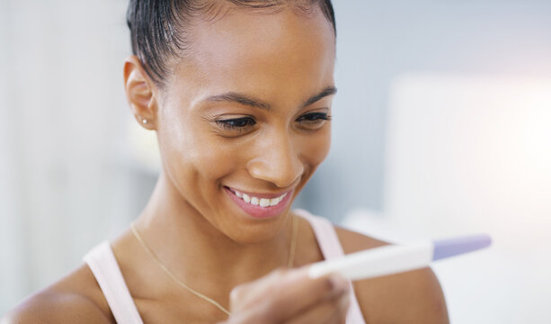 I cant believe this is finally happening. an attractive and cheerful young woman happily looking at her pregnancy test results in her bedroom at home.