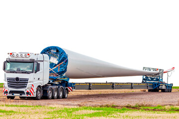 Truck on field, Isolated on white. Blade for wind turbines. Special transport of a blade for a wind...