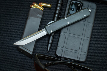 Tactical equipment and an automatic folding knife with a tanto blade shape.