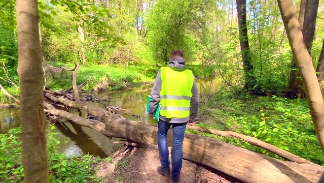 Male ecologist makes records of the state of the environment forest river. Environmental control.