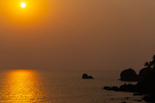 View of the sea during the sunset as seen from the Cabo De Rama at Goa in India. Sunlight makes the sea orange in color during the sun. Natural sunset beach relaxation background. 