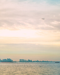 View of Singapore from the distance on the edge of the state border in the dusk with orange sky and an airplane in the sky