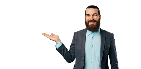 Banner size shot of a cheerful bearded man wearing jacket presenting something with his palm.