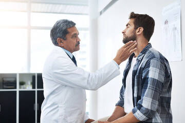 Look up for me. a mature male doctor doing a check up on a young patient whos seated on a doctors bed.