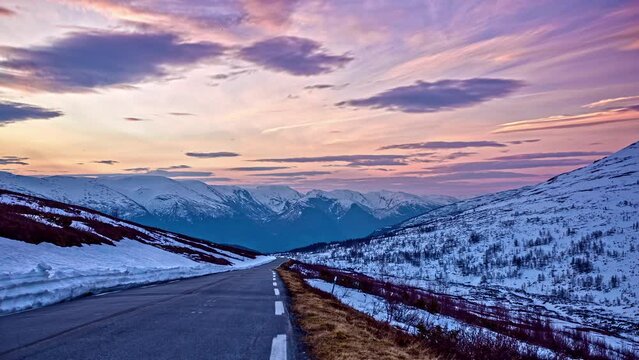 Timelapse sunset of pink and purple mountain roadway and clouds