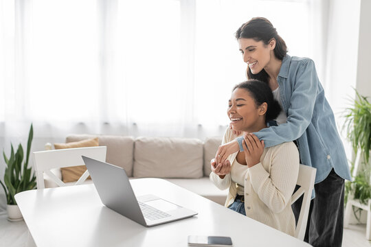 Joyful Multiethnic Lesbian Couple Showing Engagement Ring During Video Call On Laptop.