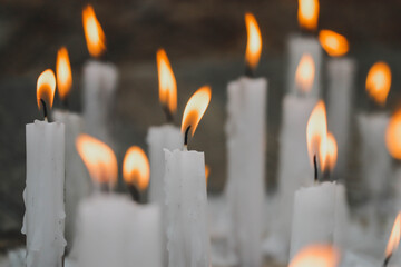 Close-up of lit white candles, partially out of focus
