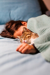 boy falls asleep and hugs his cat, who sleeps with him under the covers. children and pets. the cat...